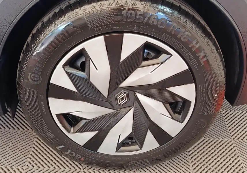 Gros plan sur la roue avant droite de la Renault Clio bleu, avec jante au design géométrique noir et argent.
