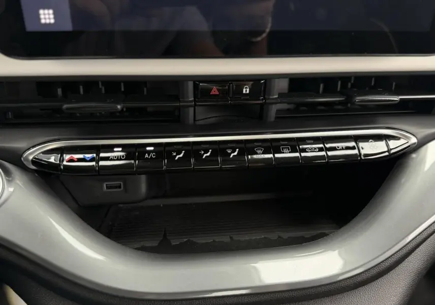 Gros plan sur la console centrale de la Fiat 500 électrique blanche 2023, montrant les commandes de climatisation et ventilation.