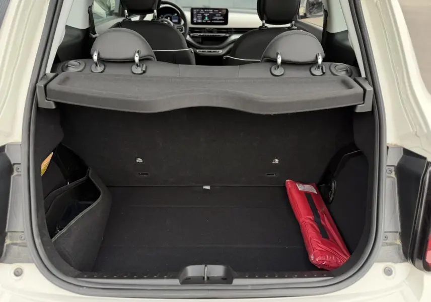 Coffre ouvert d'une FIAT 500 électrique blanche 2023, vue arrière montrant l'intérieur noir avec un kit de sécurité rouge.
