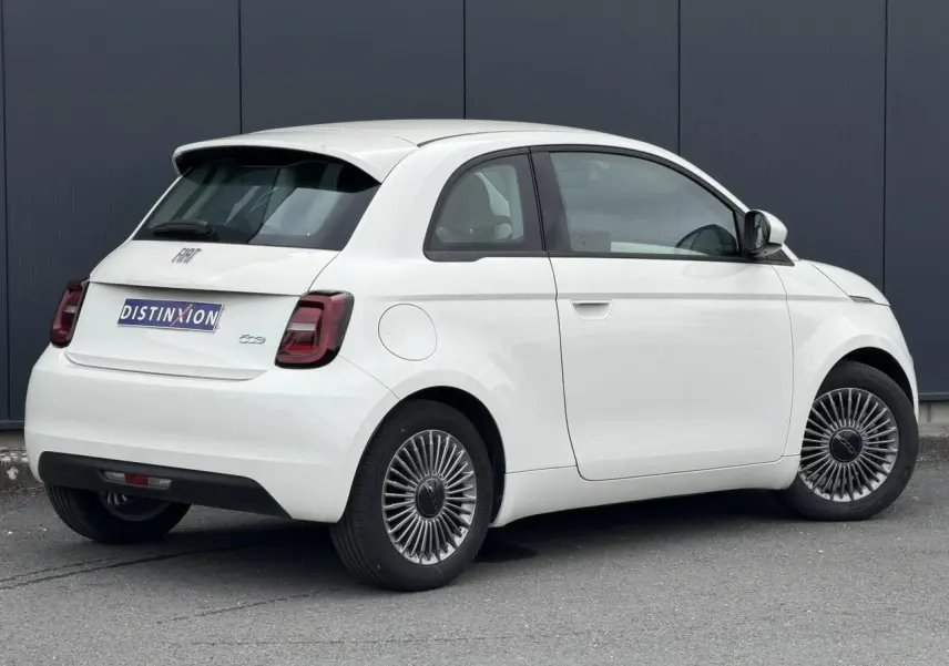 Fiat 500 électrique blanche vue 3/4 arrière droit, avec jantes stylisées et feux arrière foncés.