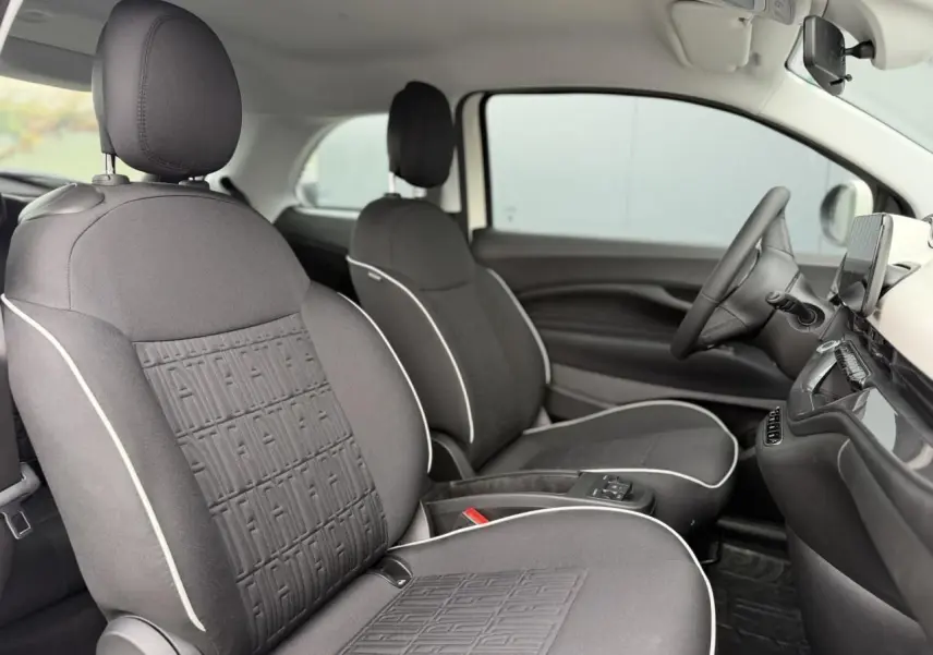 Vue intérieure côté gauche des sièges avant gris foncé avec surpiqûres blanches et motifs FIAT embossés sur une FIAT 500 électrique 2023.