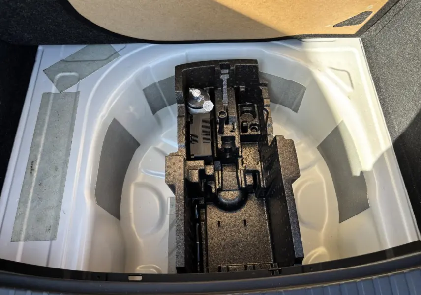 Coffre ouvert d'une Skoda Scala blanc glacier montrant le rangement pour roue de secours et outils intégrés.