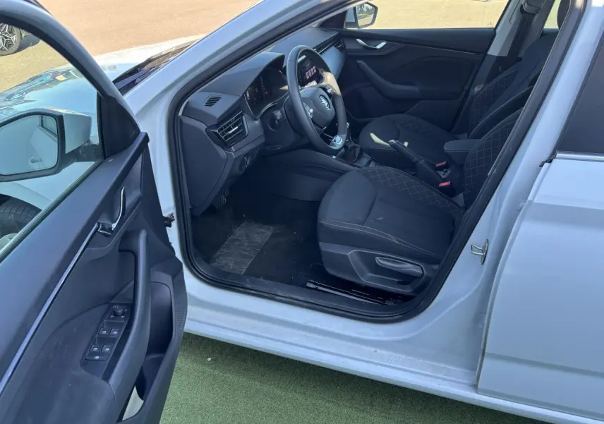 Intérieur côté conducteur d'une Skoda Scala blanc glacier 2024, montrant sièges noirs et tableau de bord moderne.
