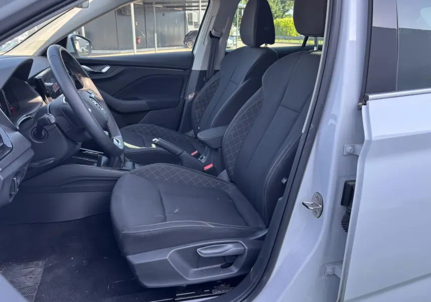 Intérieur côté conducteur du Skoda Scala blanc glacier 2024, sièges noirs avec surpiqûres et volant multifonctions visible.