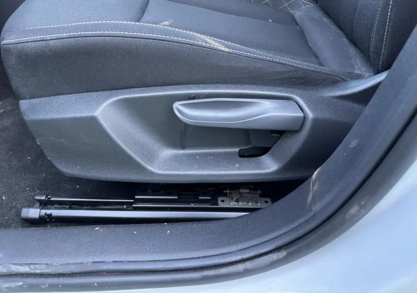 Gros plan sur la manette de réglage du siège conducteur noir de la Skoda Scala blanc glacier 2024, côté gauche.