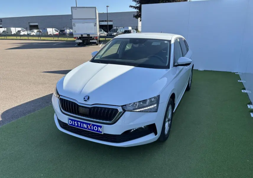 Vue 3/4 avant d'une Skoda Scala blanc glacier avec calandre noire et jantes alliage argent sur sol vert.