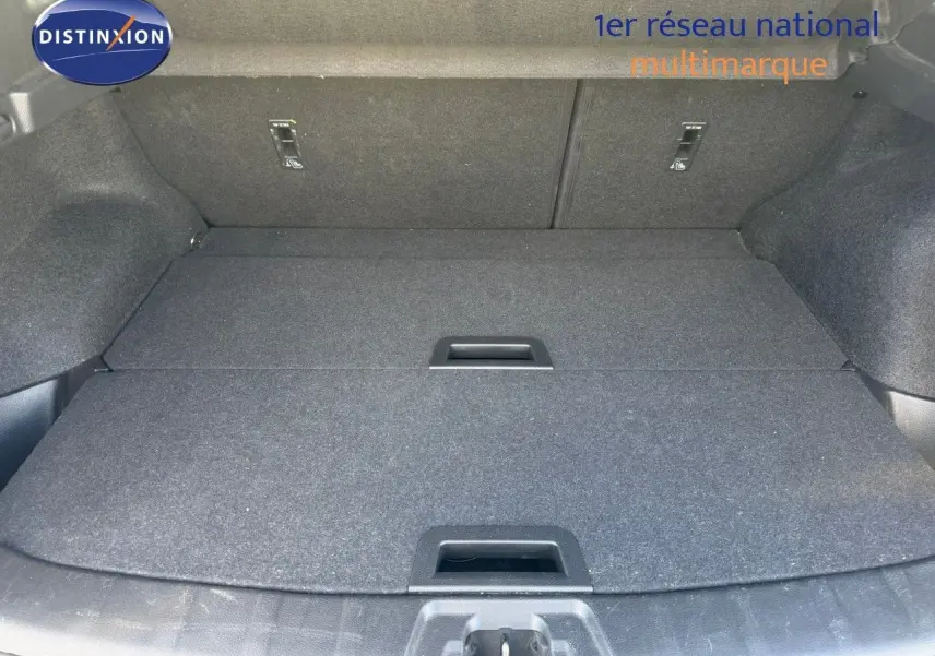 Coffre spacieux du Nissan Qashqai blanc nacré, vue plongeante montrant le plancher plat et les poignées intégrées.