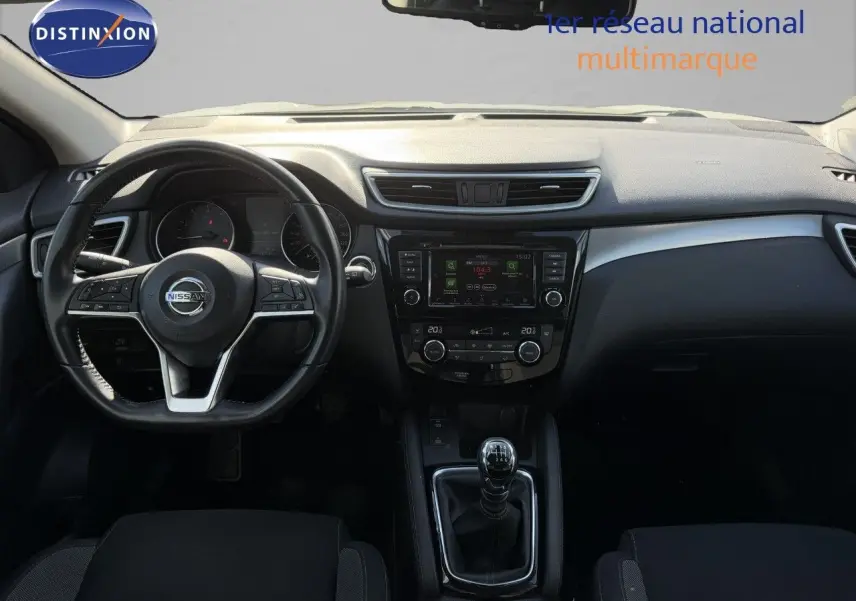 Vue intérieure frontale du tableau de bord et volant d'un Nissan Qashqai blanc nacré 2019 avec boîte manuelle.