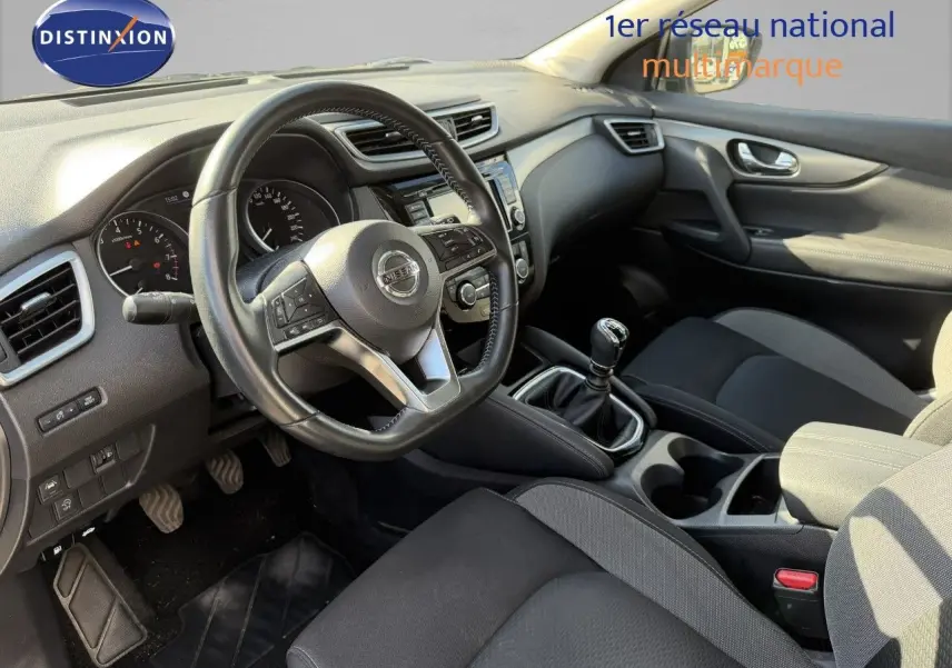 Vue intérieure côté conducteur du Nissan Qashqai blanc nacré 2019, avec volant multifonction et boîte manuelle.