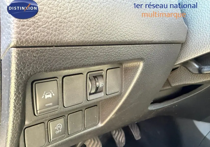 Vue intérieure du tableau de bord côté conducteur du Nissan Qashqai blanc nacré, montrant les commandes d'assistance et réglages lumineux.