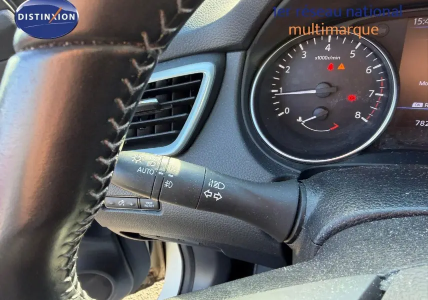Détail du volant et du combiné d'instruments du Nissan Qashqai blanc nacré, montrant les commandes d'éclairage et le compte-tours.
