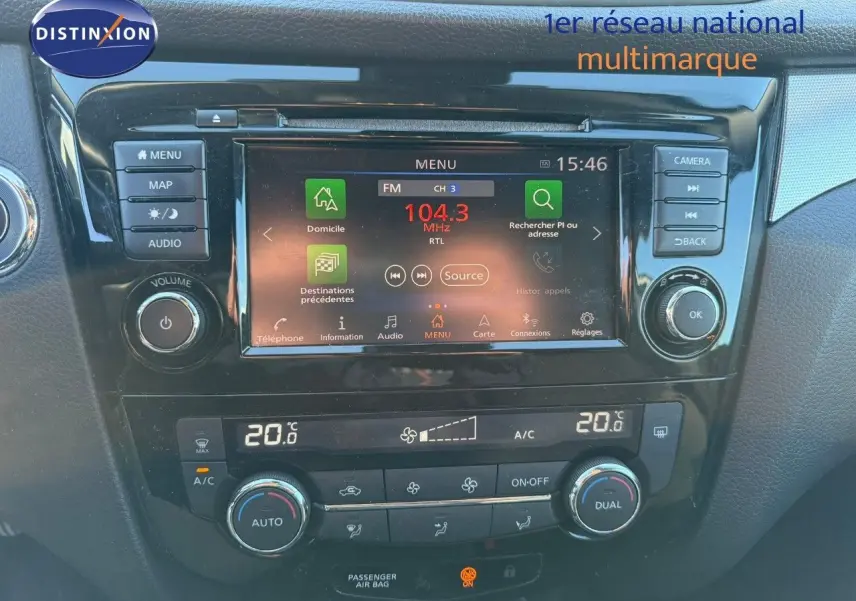 Vue rapprochée du tableau de bord du Nissan Qashqai blanc nacré, avec écran tactile et commandes de climatisation.