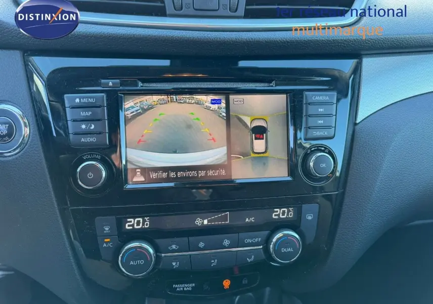 Vue rapprochée de la console centrale du Nissan Qashqai blanc nacré, avec écran de caméra de recul et commandes climatisation.