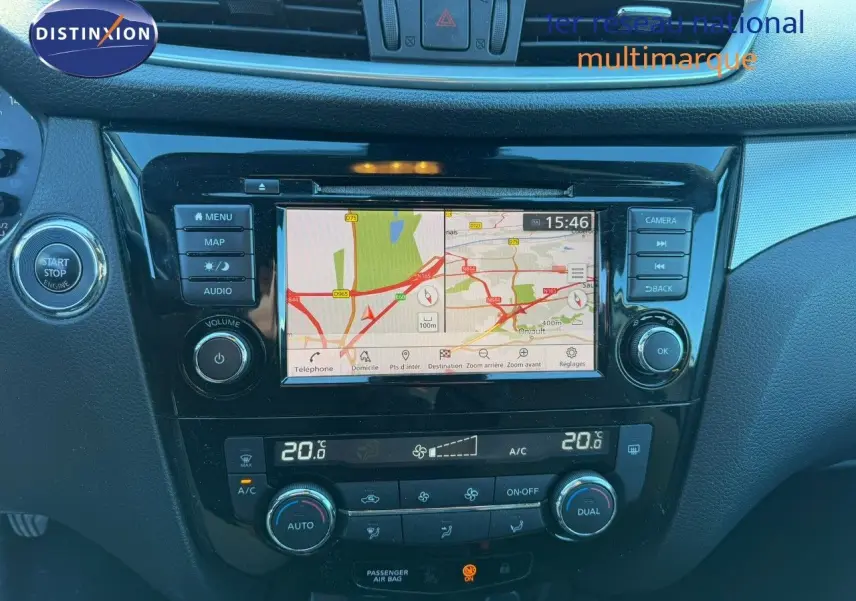 Vue rapprochée du tableau de bord du Nissan Qashqai blanc nacré, avec écran tactile de navigation et commandes climatisation.