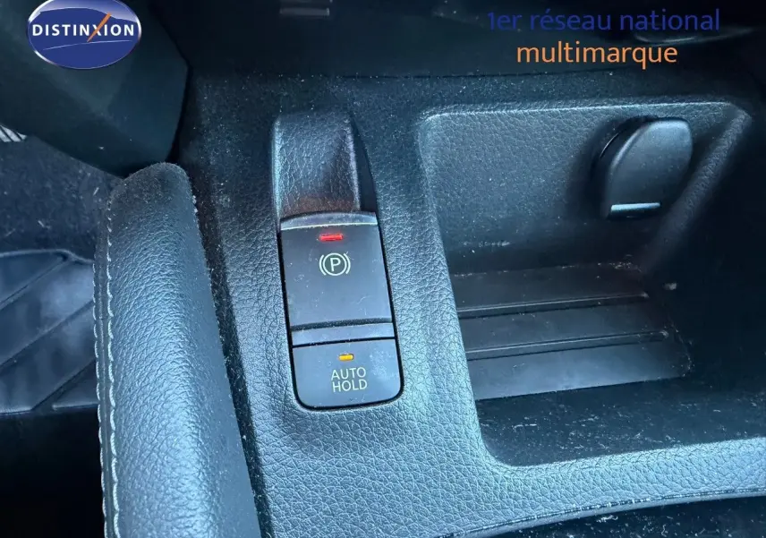 Gros plan sur la console centrale noire du Nissan Qashqai blanc nacré, montrant le frein à main électronique et le bouton Auto Hold.