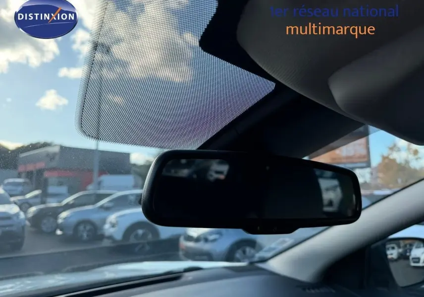 Rétroviseur intérieur du Nissan Qashqai blanc nacré, vue depuis l’habitacle avec ciel et voitures en arrière-plan flous.