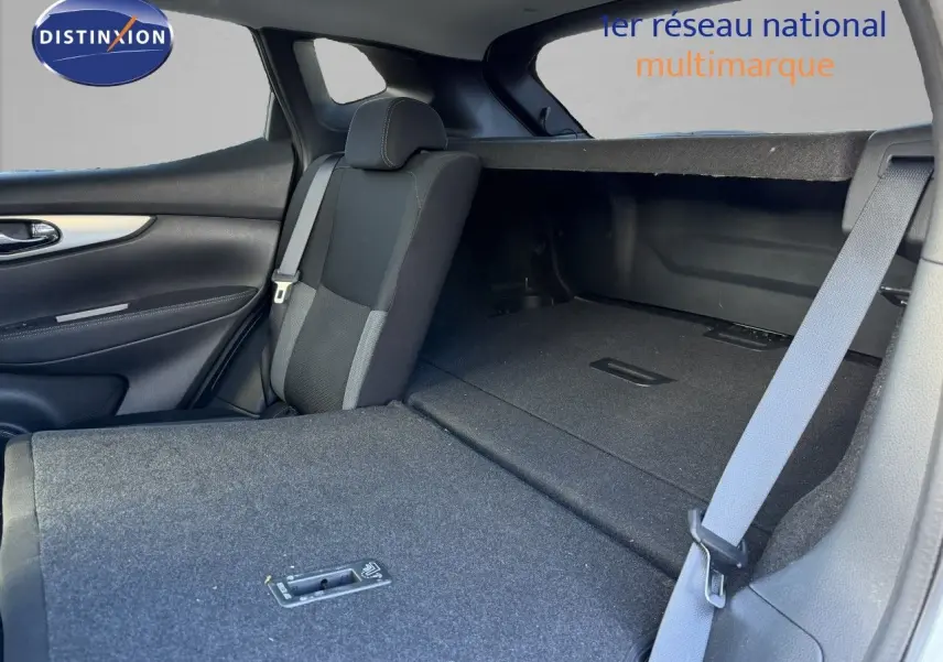 Vue intérieure arrière du Nissan Qashqai blanc nacré, siège rabattable et espace de coffre visible.