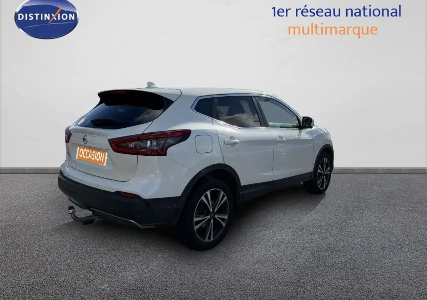 Vue 3/4 arrière droite d'un Nissan Qashqai blanc nacré avec jantes noires et attelage visible.