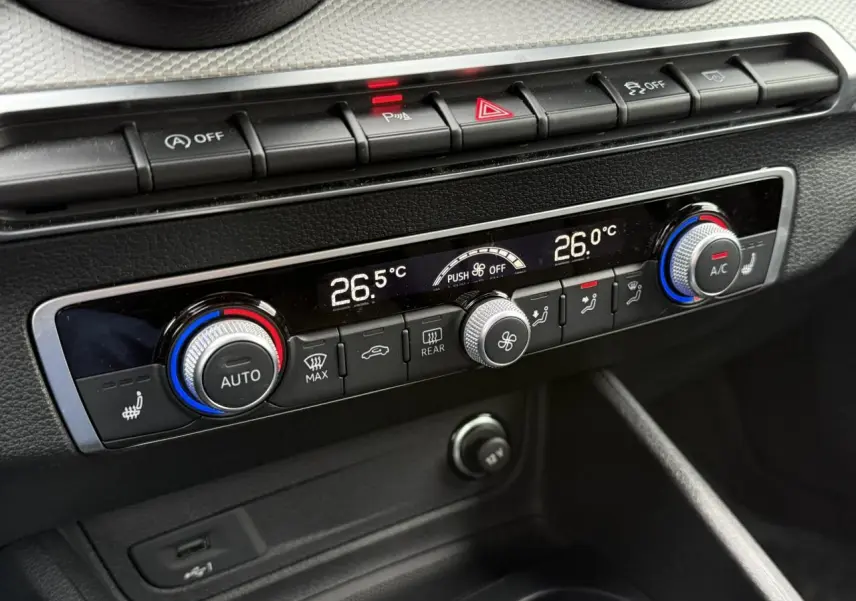 Détail de la console centrale de l'Audi Q2 35 TFSI S-Line 2023, montrant la climatisation automatique bi-zone avec commandes digitales.