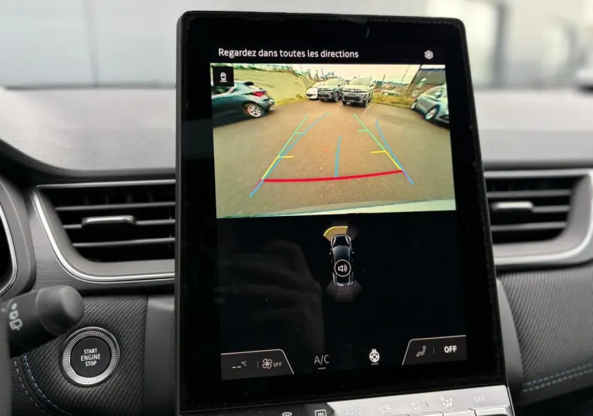 Écran central tactile du Renault Captur 2025 affichant la caméra de recul avec aides au stationnement, intérieur gris et coutures bleues.