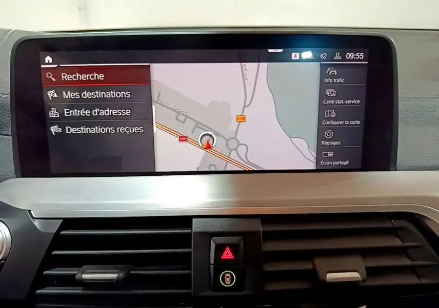 Vue intérieure du tableau de bord de la BMW X3 noir, écran tactile de navigation affichant une carte en mode recherche.