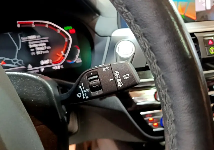 Gros plan sur la manette de commande des essuie-glaces à gauche du volant cuir noir du BMW X3 sDrive18d 2019, tableau de bord numérique visible.