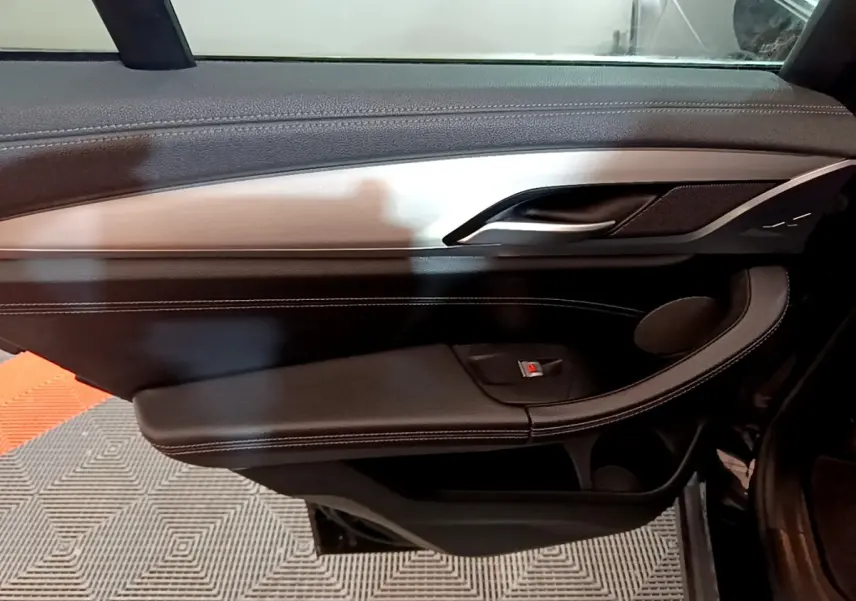 Vue intérieure du panneau de porte côté gauche noir avec insert aluminium brossé et commande de lève-vitre BMW X3 2019.