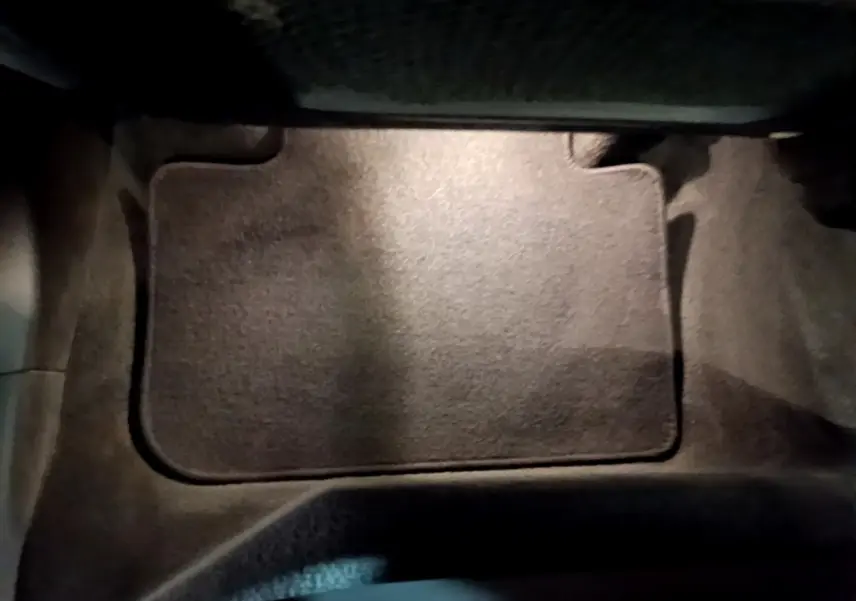 Tapis de sol noir dans l'habitacle avant d'une BMW X3 sDrive18d 2019, vue en plongée rapprochée.