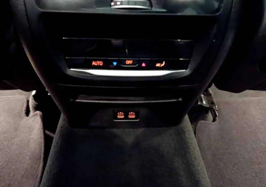Détail de la console centrale arrière noire du BMW X3 sDrive18d 2019 avec commandes climatisation et ports USB éclairés.