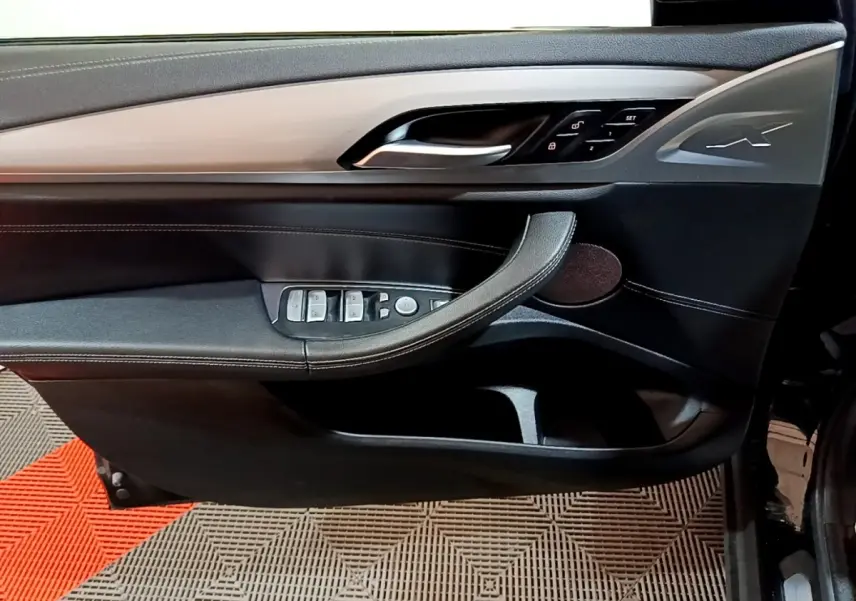 Vue intérieure côté gauche de la porte BMW X3 sDrive18d 2019 noire, avec commandes électriques et insert aluminium.