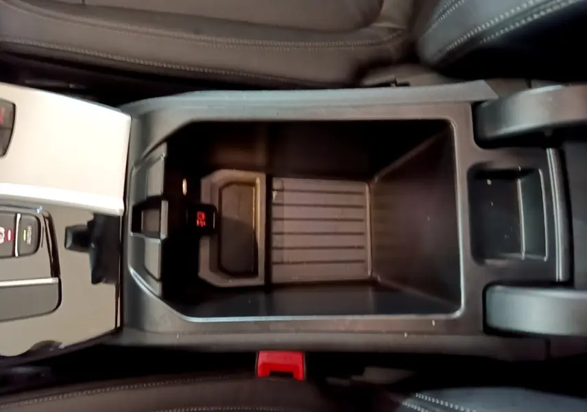 Vue plongeante sur le rangement central noir entre les sièges en cuir marron du BMW X3 sDrive18d 2019.