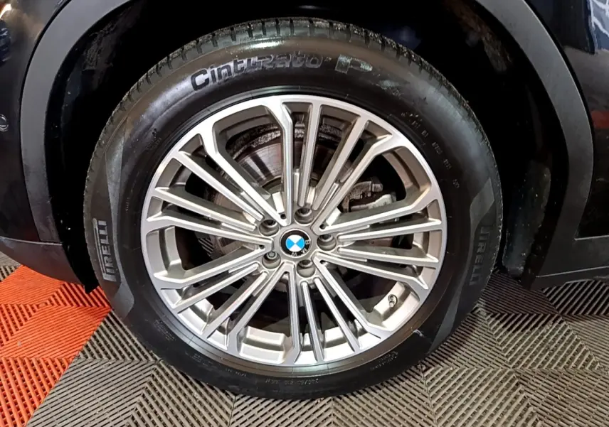 Gros plan sur la roue avant droite d’un BMW X3 noir, jante alliage multi-branches et pneu Pirelli.
