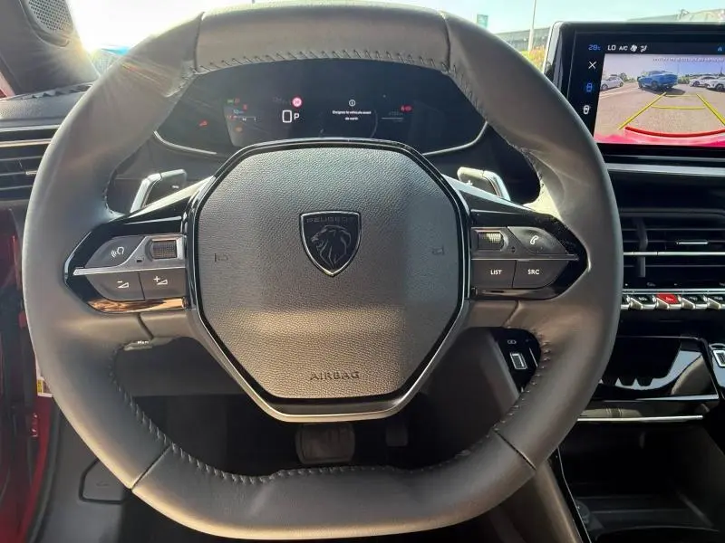 Vue rapprochée du volant cuir noir du Peugeot 2008 Hybrid 2025, avec tableau de bord numérique et écran multimédia affichant la caméra de recul.