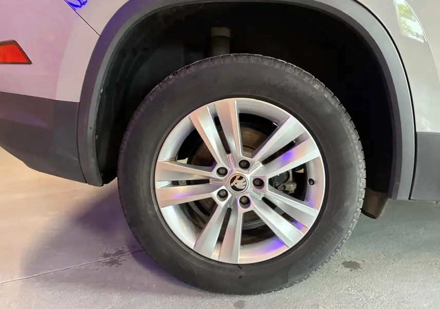 Gros plan sur la roue avant droite d'un Skoda Kodiaq gris clair, mettant en valeur la jante alliage et le logo central.