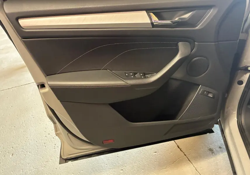 Vue rapprochée de la porte avant gauche du Skoda Kodiaq gris clair, avec garniture noire et insert bois clair.