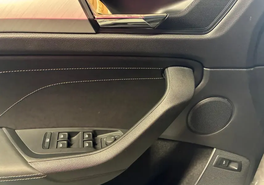 Détail de la porte côté conducteur du Skoda Kodiaq gris clair 2023, avec commandes des vitres et haut-parleur intégré.