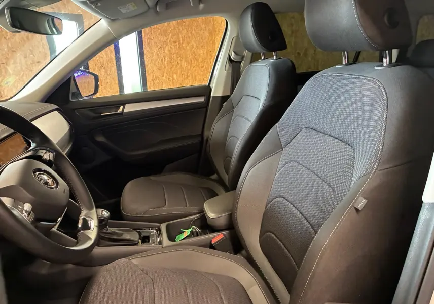 Vue intérieure côté conducteur du Skoda Kodiaq gris clair 2023, sièges tissu noir et tableau de bord moderne.