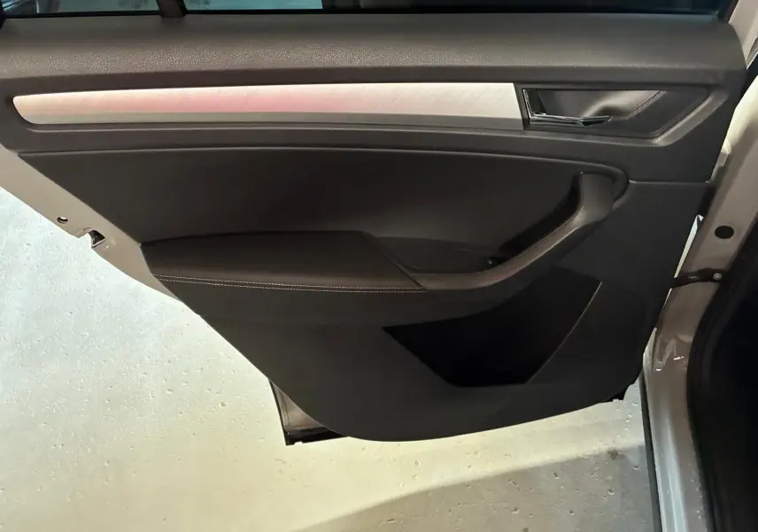 Vue rapprochée de la porte avant gauche gris clair d’un Skoda Kodiaq 2023 avec garniture noire et insert métal brossé.