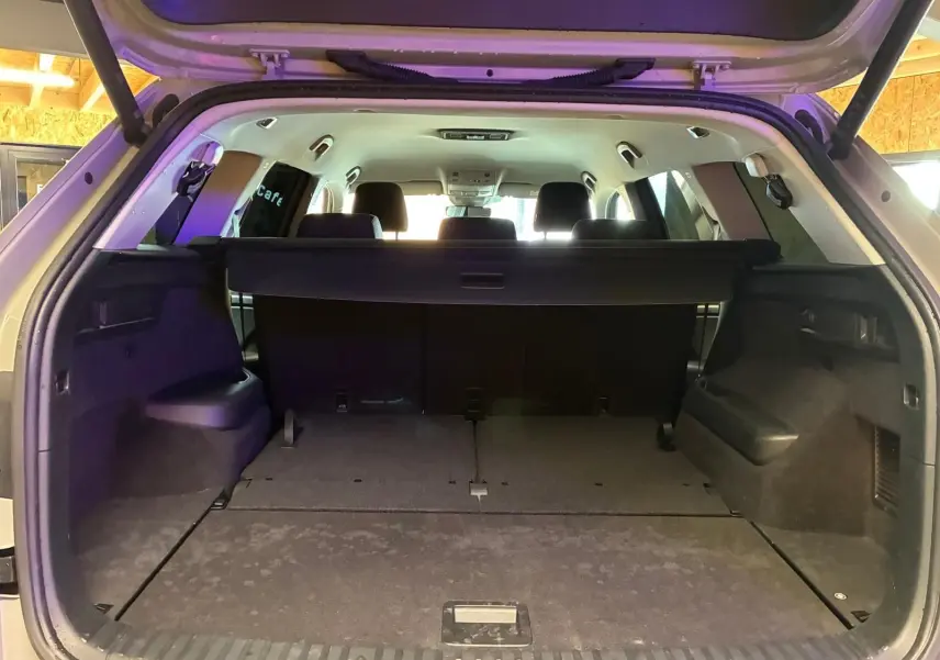 Coffre ouvert vu de l'arrière d'un Skoda Kodiaq gris clair 2023, montrant l'espace de chargement et la banquette arrière noire.