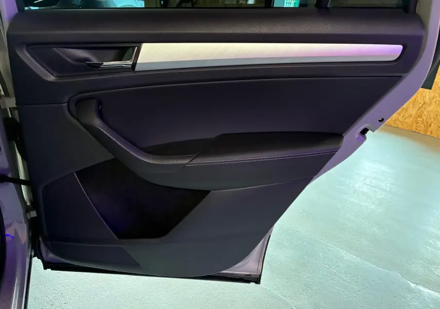 Vue intérieure de la porte arrière gauche du Skoda Kodiaq gris clair 2023, avec garniture noire et insert argenté.