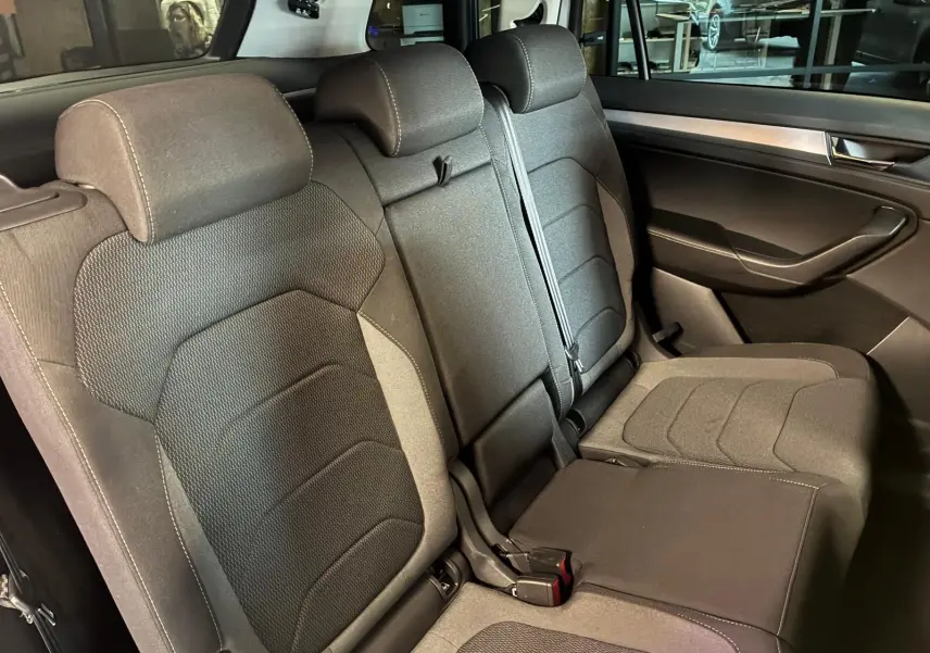 Vue intérieure sur la banquette arrière en tissu noir du Skoda Kodiaq 2023, avec ceinture et habillage de porte visible.