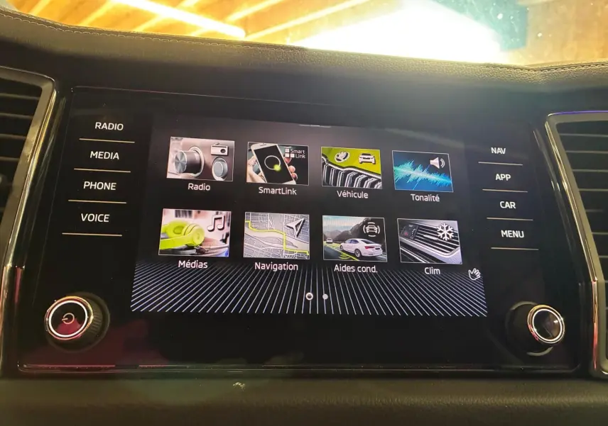 Écran tactile central du Skoda Kodiaq gris clair 2023, affichant le menu principal avec options multimédia et navigation.