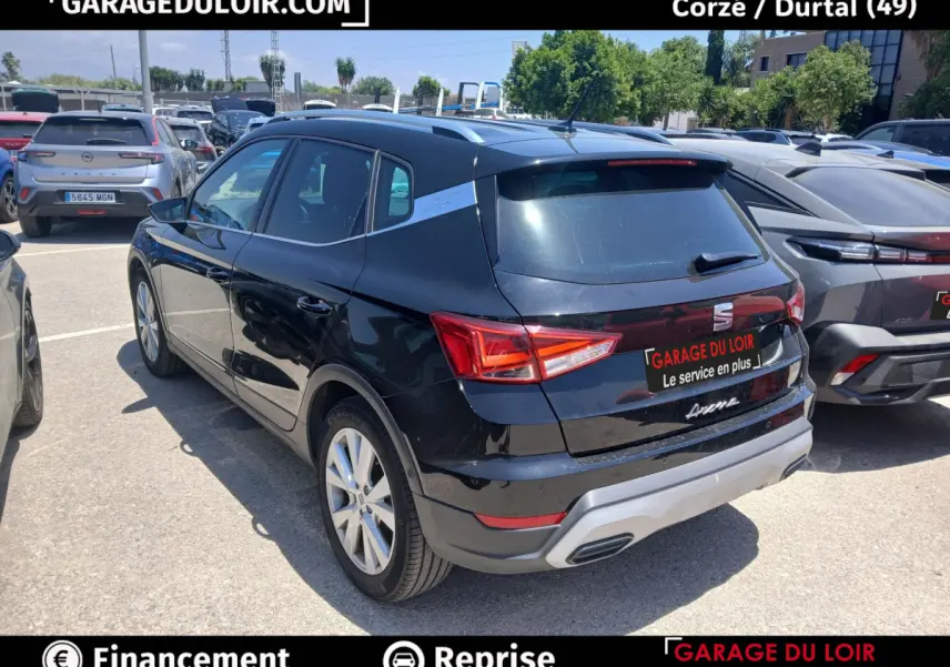 Vue 3/4 arrière droite d'un SEAT Arona noir avec toit et rails argentés, garé en extérieur sur parking.