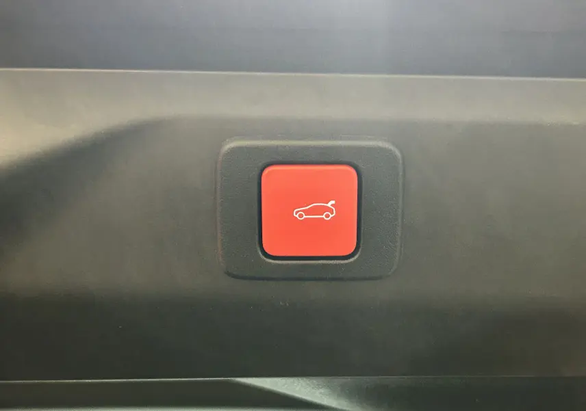Bouton rouge intérieur de Peugeot 3008 Hybrid 2026 pour ouverture électrique du hayon, vue rapprochée.