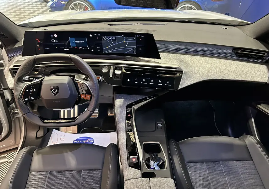 Vue intérieure du tableau de bord et volant du Peugeot 3008 Hybrid 2026 avec finition tissu et inserts gris clair.