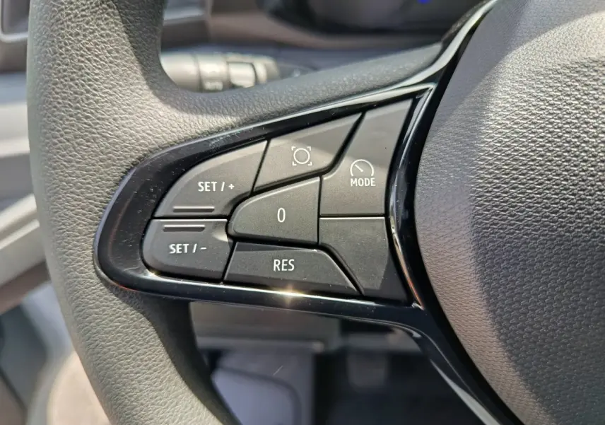 Gros plan sur les commandes de régulateur de vitesse au volant du Renault Master, boutons noirs sur fond gris texturé.