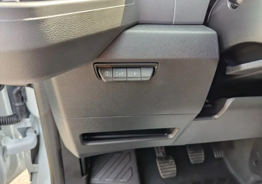Détail intérieur côté gauche du tableau de bord noir avec commandes de réglage des phares et verrouillage sur Renault Master blanc.