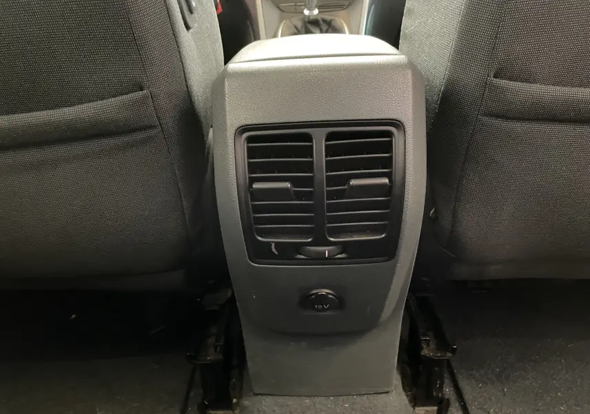 Bouche d'aération arrière centrale avec prise 12V entre les sièges avant d'un Ford C-MAX gris de 2012.