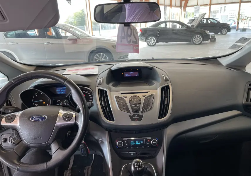 Vue intérieure du tableau de bord et volant noir de la Ford C-MAX gris 2012 avec boîte manuelle, en lumière naturelle.