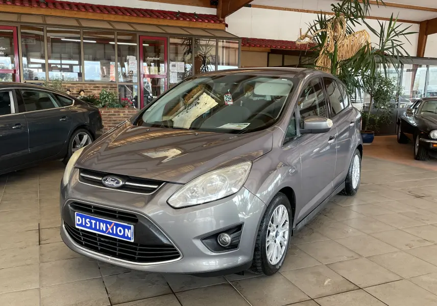 Ford C-MAX gris vue 3/4 avant droit en intérieur, avec jantes alliage et calandre distinctive Ford.